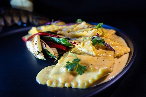 Ravioli with creamy sauce and grilled vegetables, showcasing a relaxed dining experience at The Duck Blind Grille.