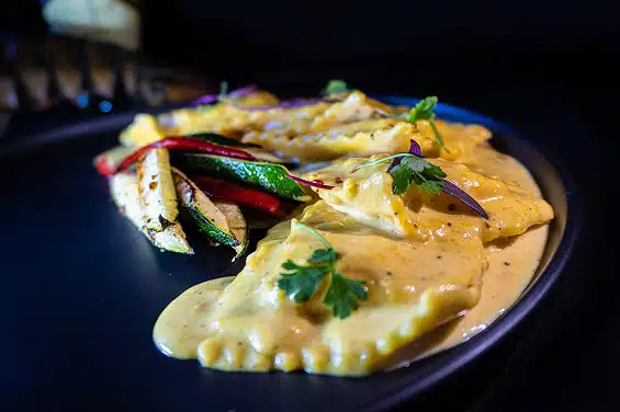 Ravioli with creamy sauce and grilled vegetables, showcasing a relaxed dining experience at The Duck Blind Grille.