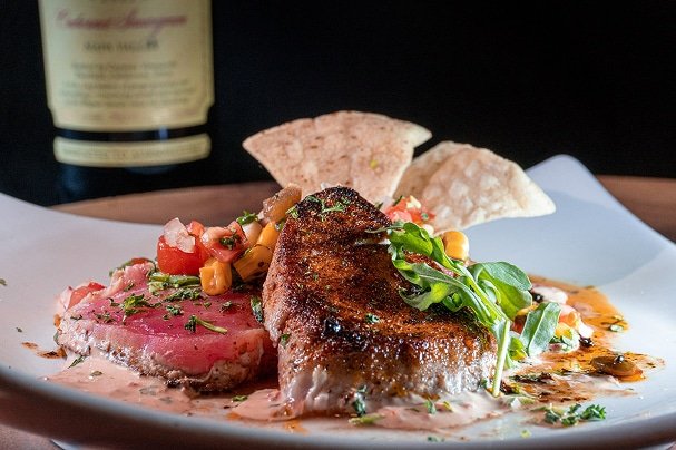 Grilled tuna steak and seared ahi tuna with fresh salsa and crispy tortilla chips, presented on a white plate, highlighting the culinary offerings at The Duck Blind Grille.