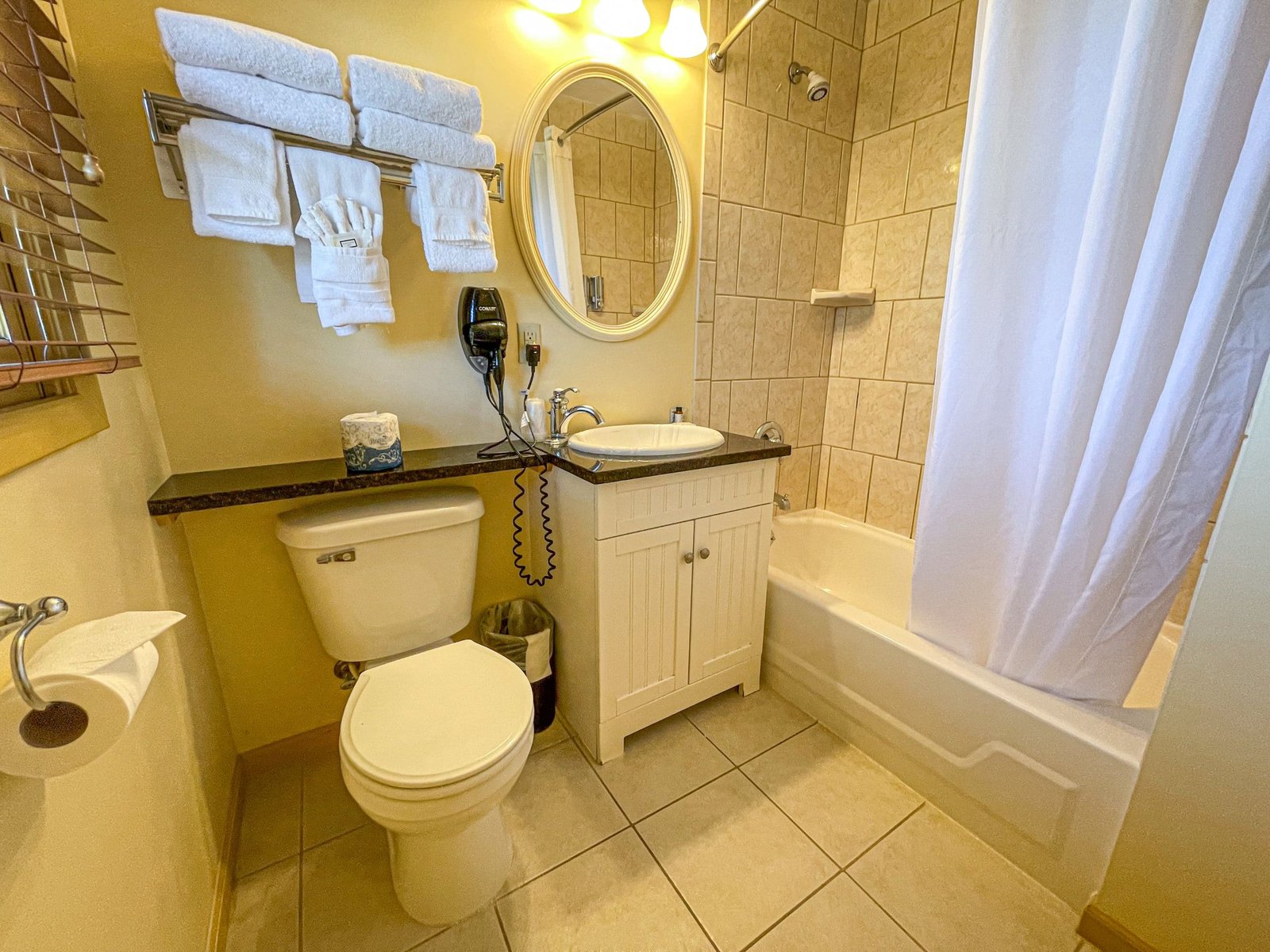 Bathroom interior featuring a tub/shower combination, vanity with sink, and plush towels, showcasing amenities for a comfortable stay at Blue Spruce Lodge.