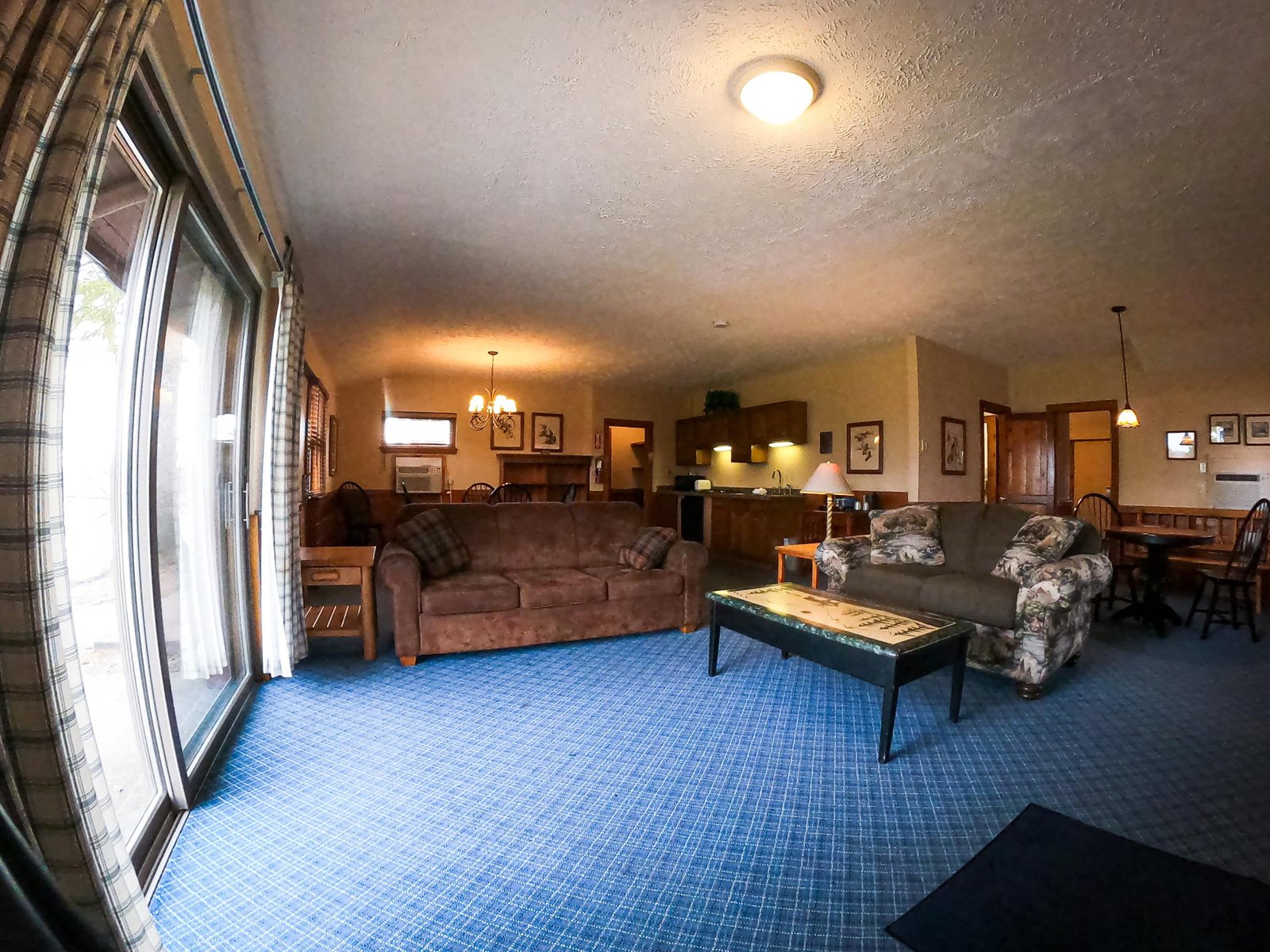Spacious living area of a 2 bedroom chalet at Otsego Resort, featuring a sofa, kitchenette, dining area, and large windows with natural light.