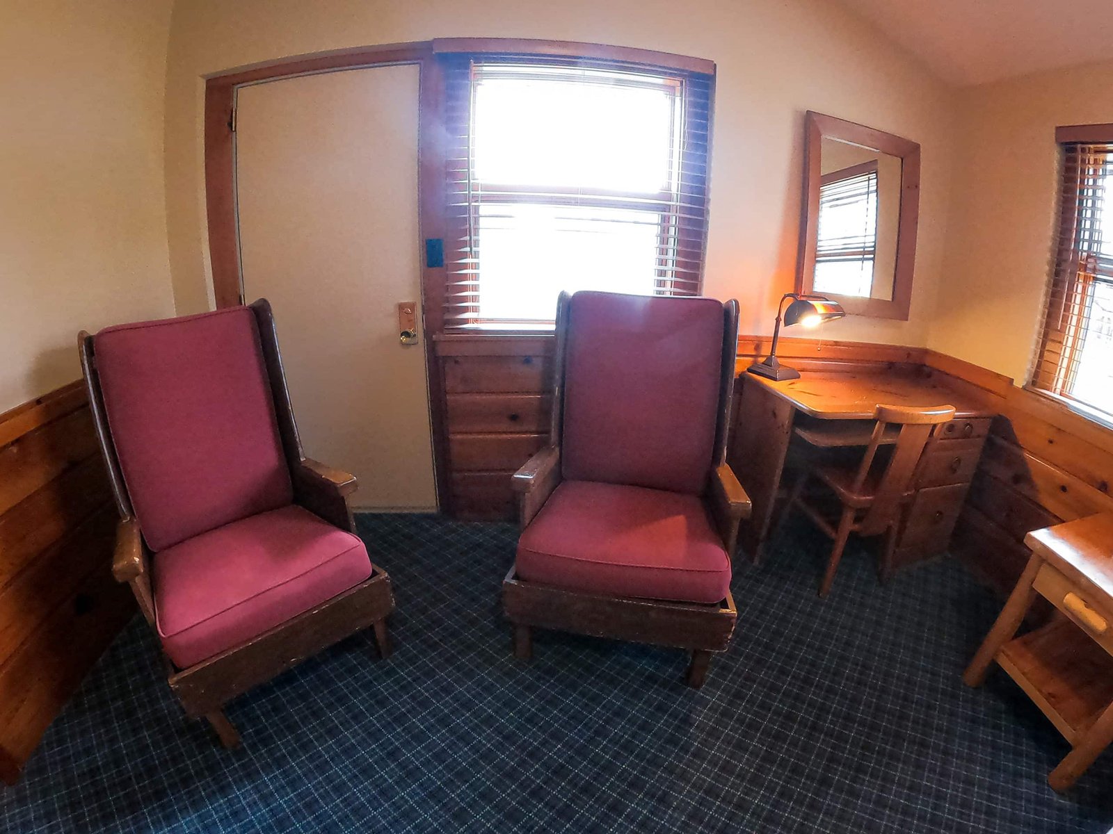 Cozy interior of a chalet at Otsego Resort featuring two upholstered chairs, a wooden desk with a lamp, and natural light from windows, emphasizing the inviting atmosphere and spacious design of the accommodations.