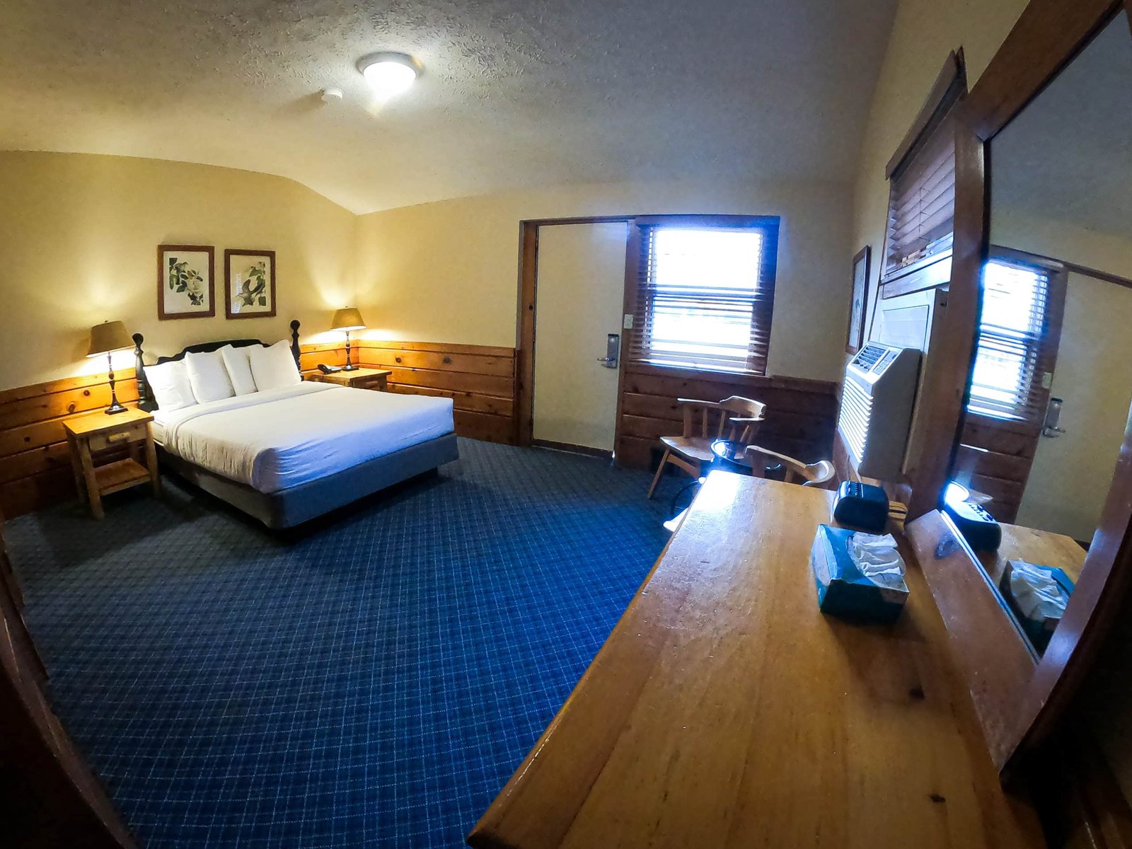 Spacious chalet interior featuring a queen bed, bedside tables with lamps, and a cozy seating area, highlighting the inviting atmosphere of Otsego Resort accommodations.