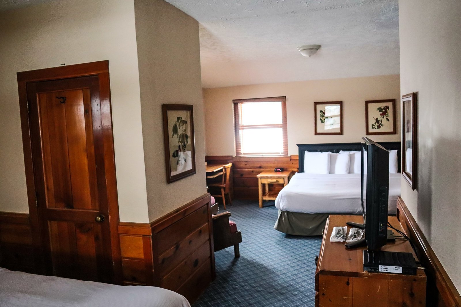 Spacious chalet interior featuring a two-bedroom layout, wooden furnishings, flat screen TV, and natural light from windows, ideal for guests at Otsego Resort.