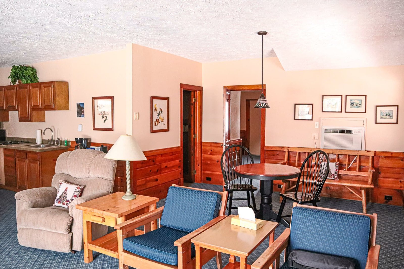 Spacious living area in a two-bedroom chalet at Otsego Resort, featuring a kitchenette, comfortable seating, and dining table, designed for relaxation and family gatherings.