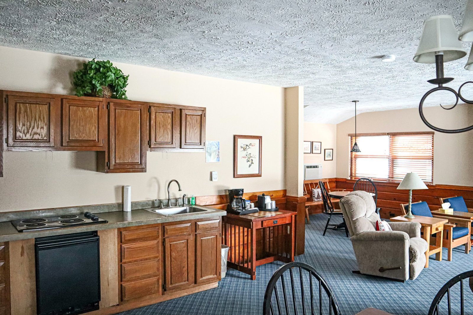 Spacious chalet interior featuring a kitchenette with stovetop and sink, living area with comfortable seating, and dining space, designed for guest comfort at Otsego Resort.