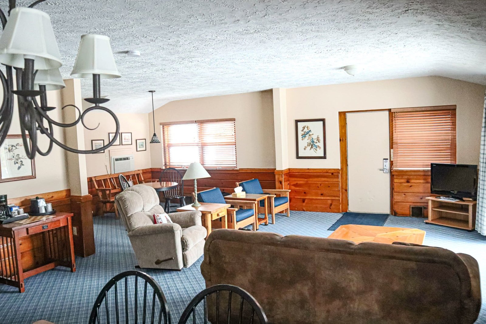 Spacious living room in a chalet at Otsego Resort, featuring a comfortable sofa, kitchenette area, dining table, and flat-screen TV, designed for guests to relax and enjoy their stay.
