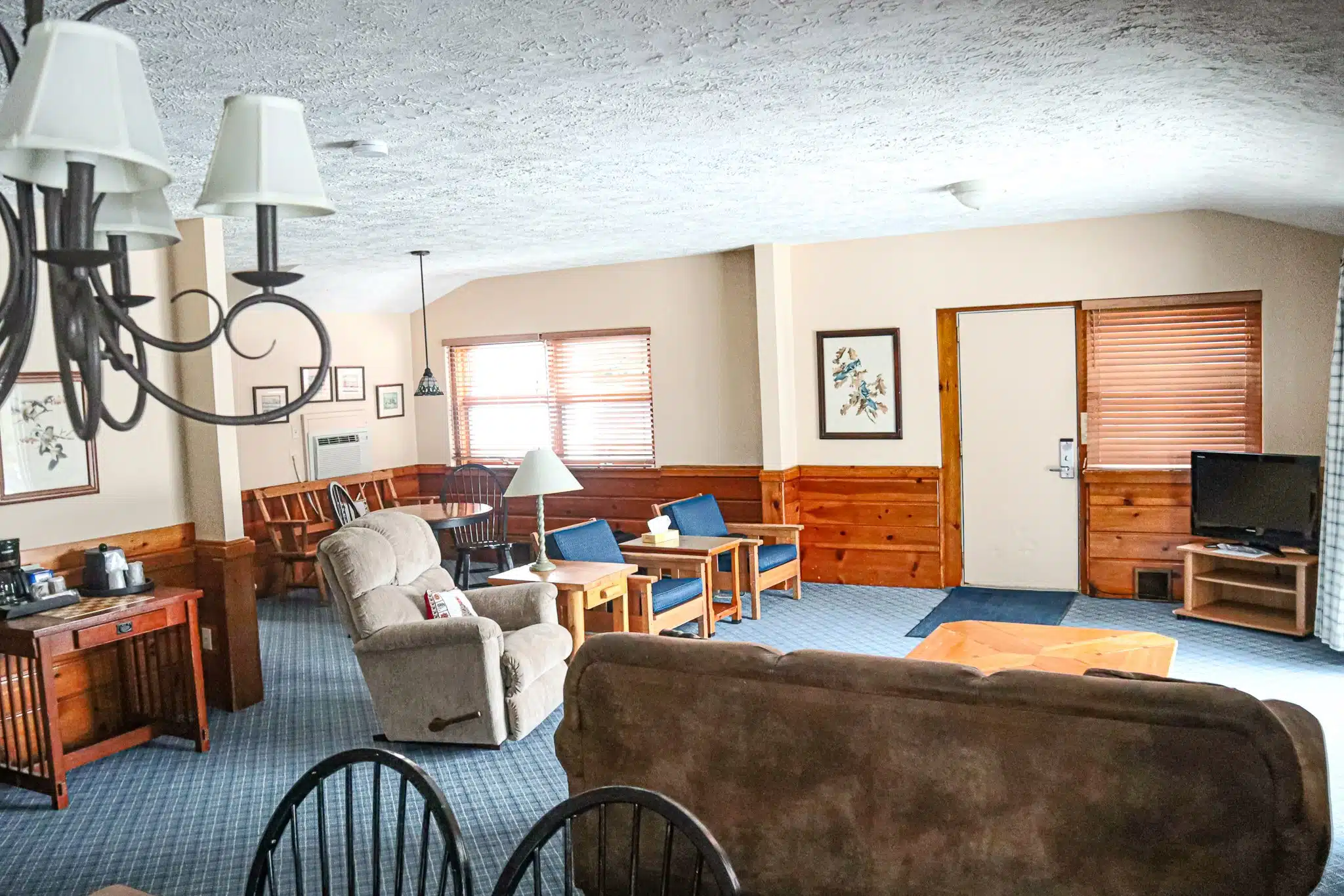 Spacious living room in a chalet at Otsego Resort, featuring a comfortable sofa, kitchenette area, dining table, and flat-screen TV, designed for guests to relax and enjoy their stay.
