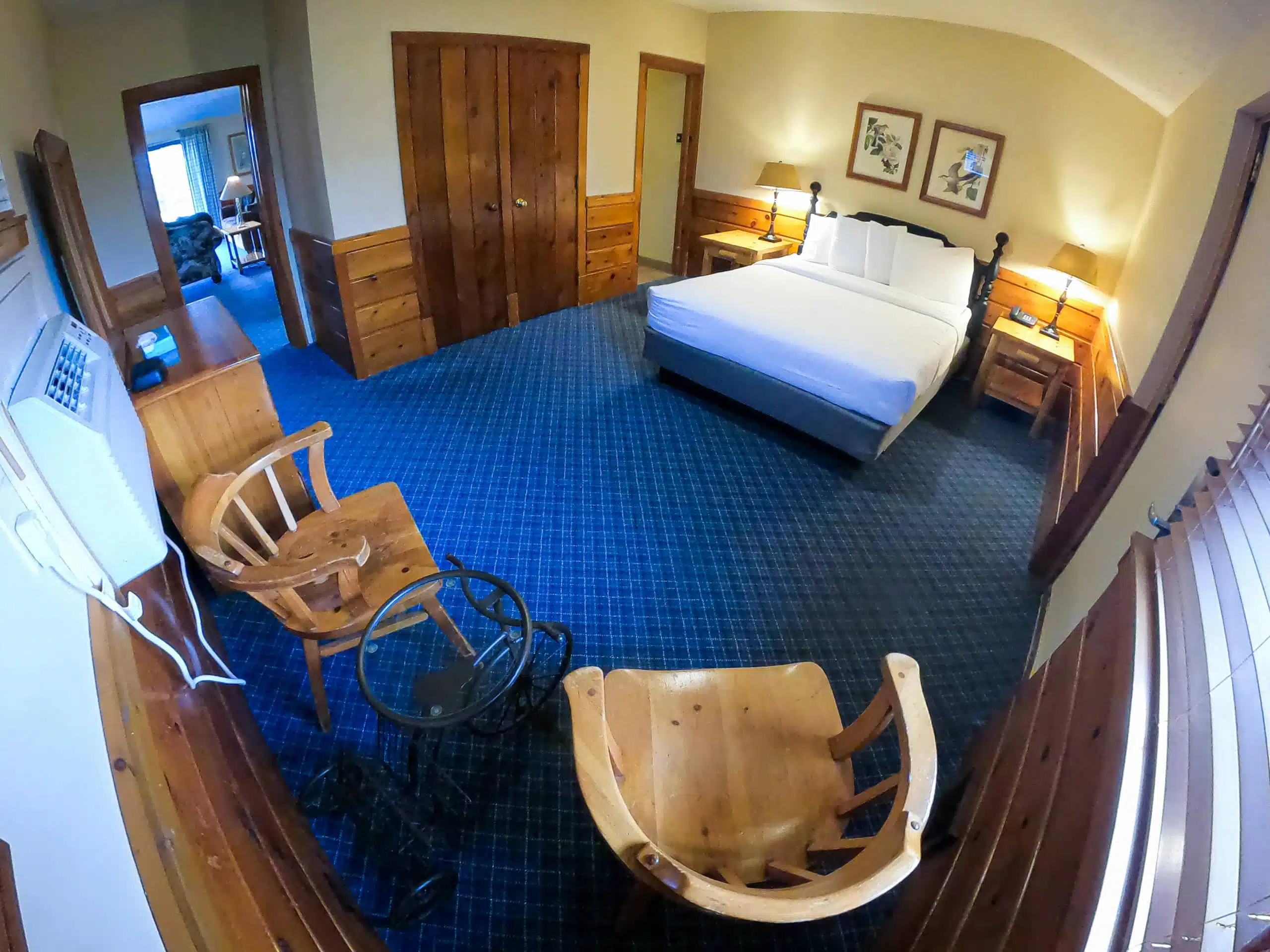 Spacious chalet interior featuring a queen bed, wooden furniture, and kitchenette, designed for comfort at Otsego Resort.