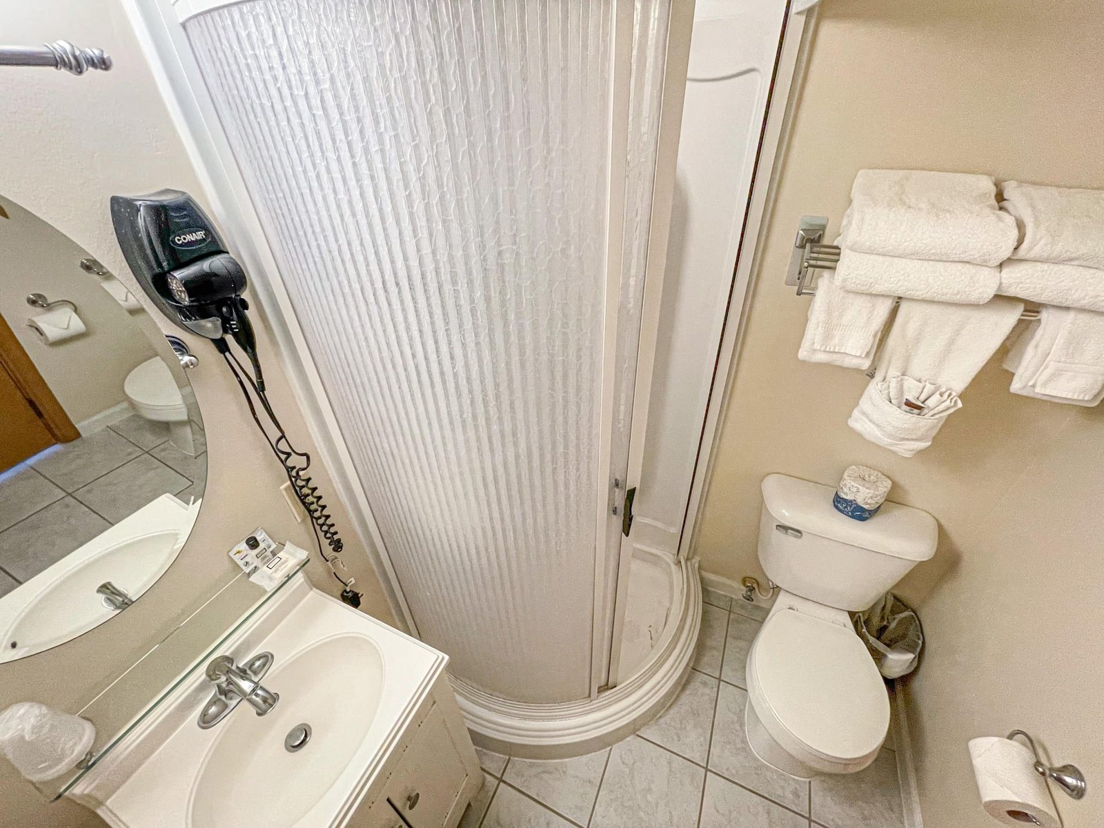 Bathroom interior featuring a stand-up shower, sink with mirror, toilet, and amenities like towels and a hairdryer, reflecting the comfort and convenience offered at the Loft Lodge in Otsego Resort.