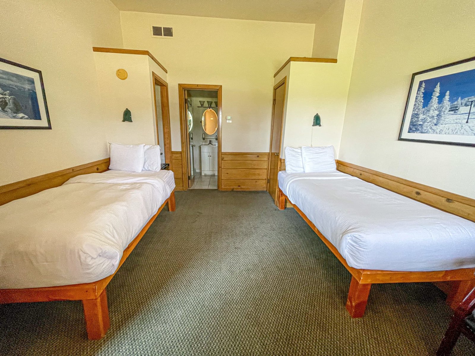 Loft Lodge room featuring two twin beds, wooden furnishings, and an ensuite bathroom, showcasing a cozy northern Michigan accommodation.