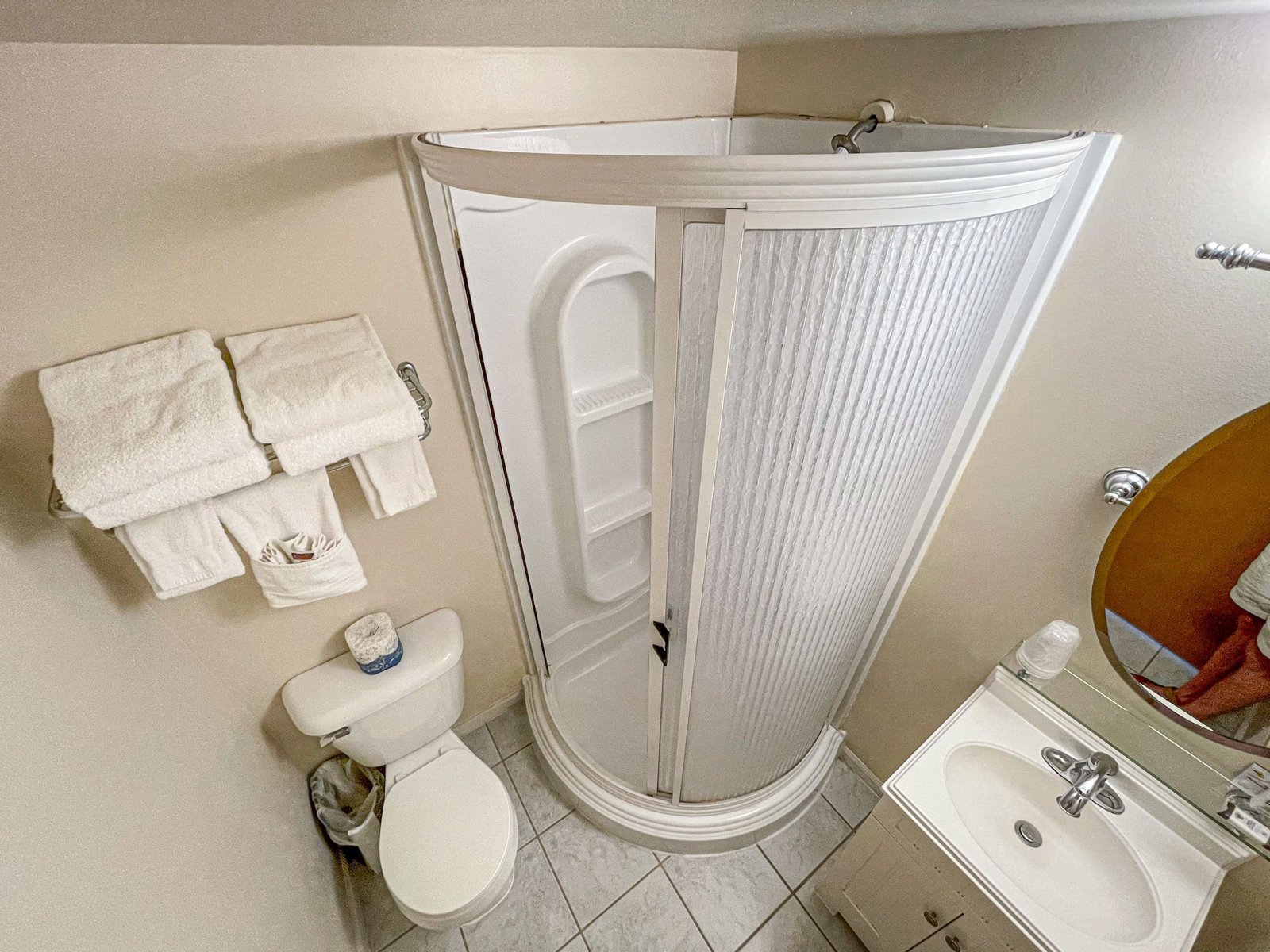 Bathroom featuring a stand-up shower, white towels, a toilet, and a sink with spa amenities, reflecting the comfort and convenience of accommodations at the Loft Lodge, Otsego Resort.