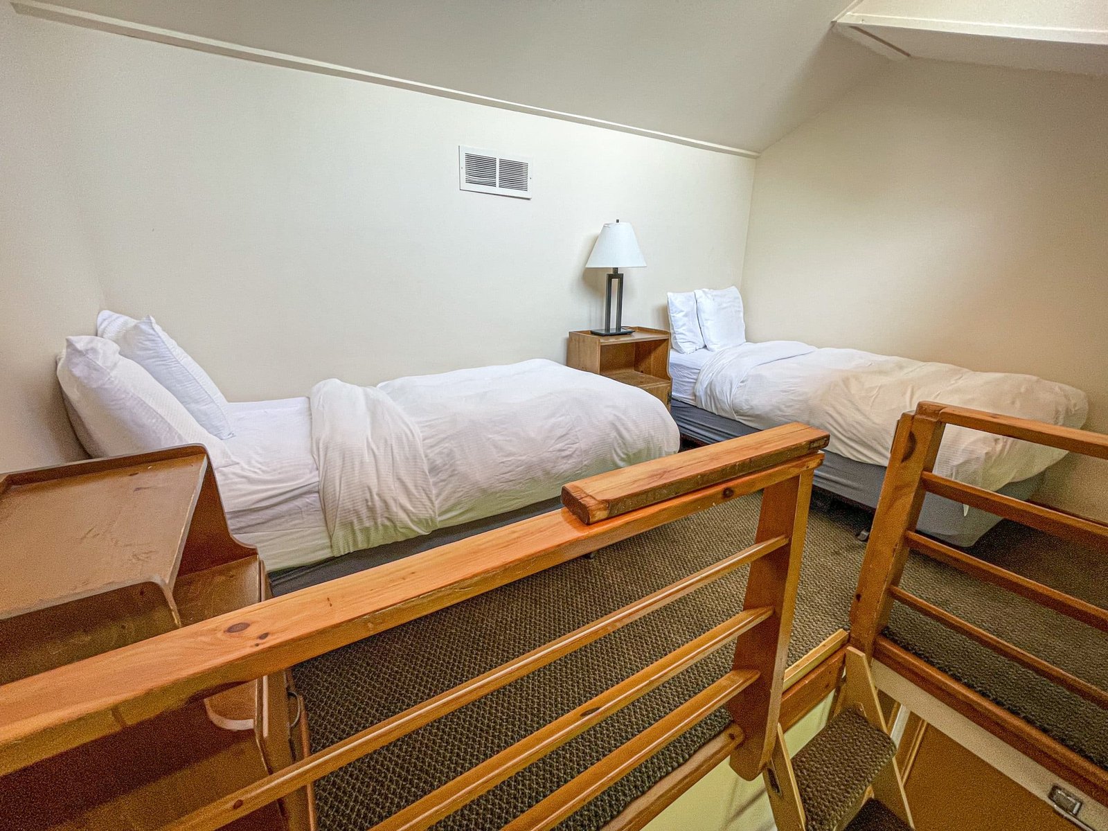 Loft Lodge room featuring two twin beds, wooden furniture, and a cozy interior, showcasing accommodations at Otsego Resort in northern Michigan.