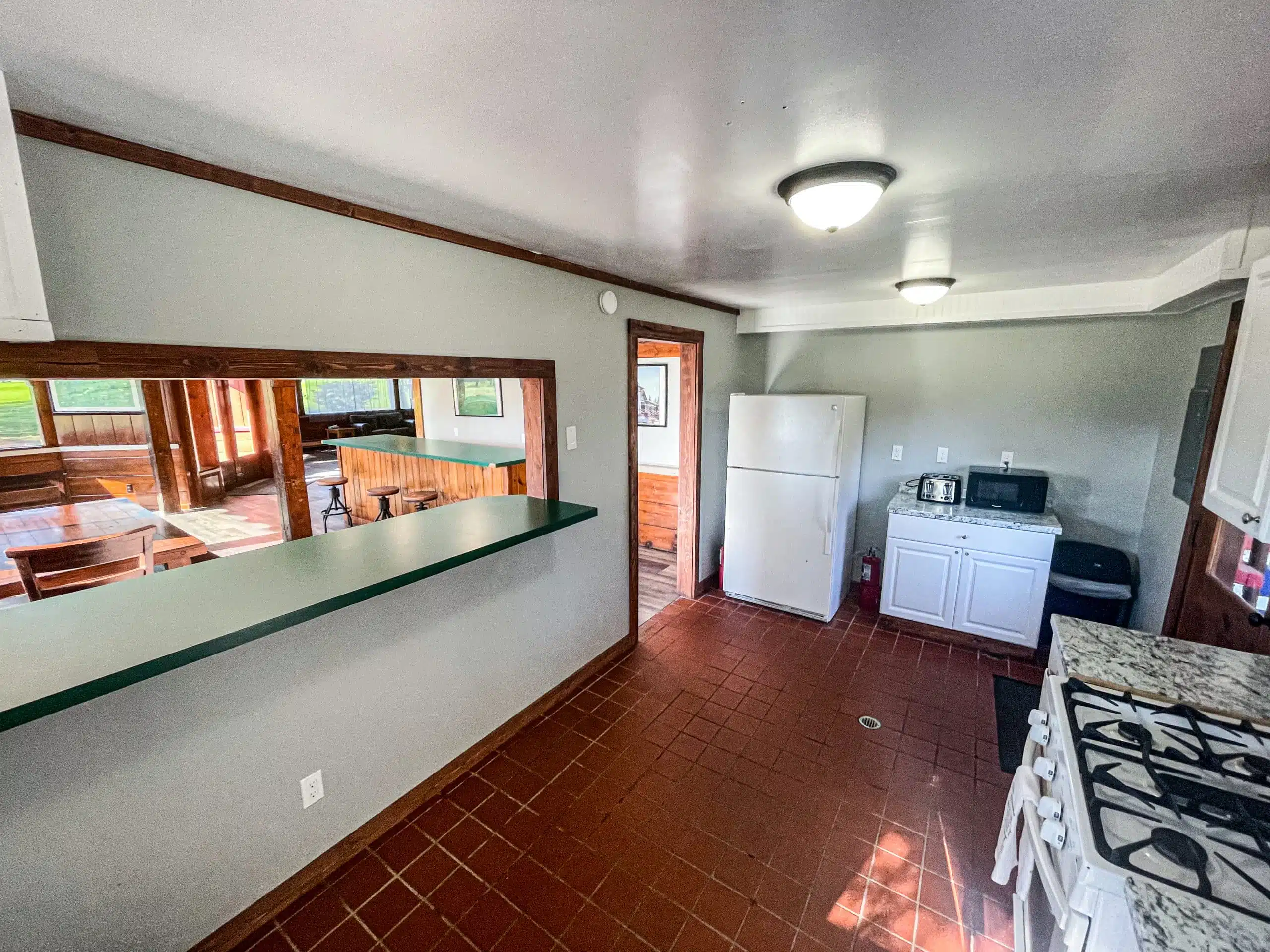 Renovated kitchen area in the Classic Lodge at Otsego Resort, featuring a full-size refrigerator, stove, and bar counter, with an open view to the living space.