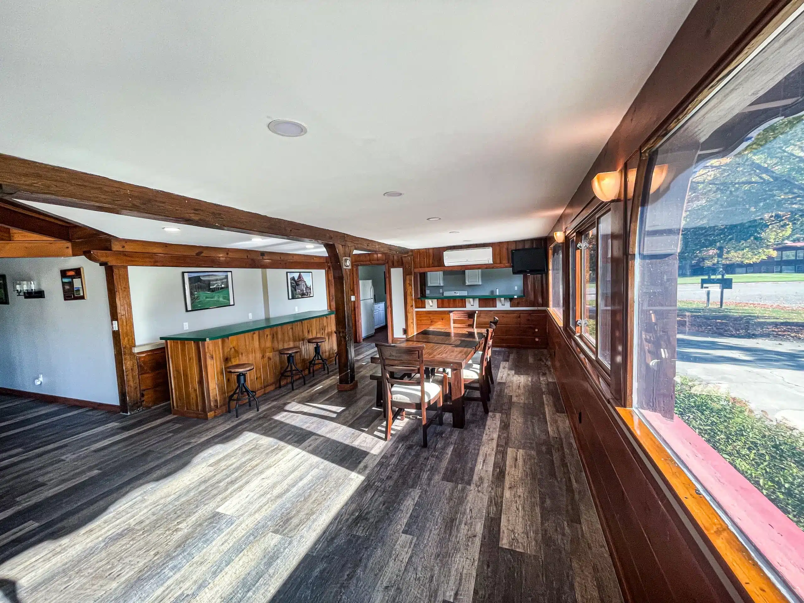 Interior view of the Classic Lodge at Otsego Resort, featuring a large living area with a dining table, bar area, and large windows, showcasing a cozy atmosphere and modern amenities.