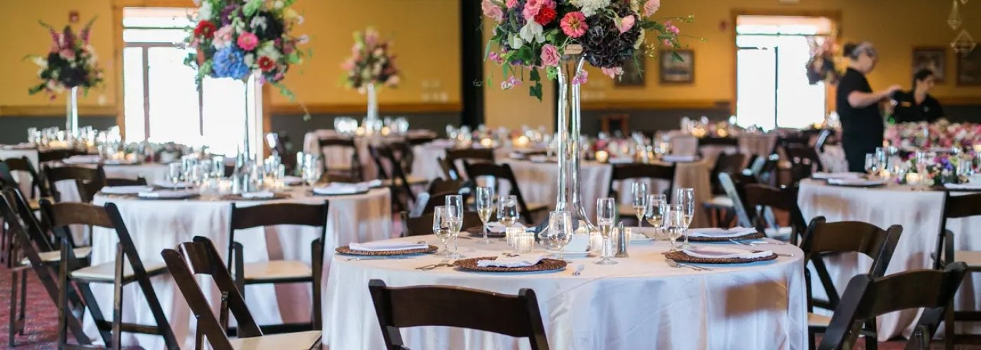 Elegant wedding reception setup at Otsego Resort featuring round tables adorned with floral centerpieces, glassware, and white linens, highlighting the venue's charming atmosphere for celebrations.